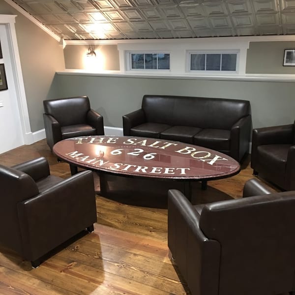 Cozy lounge area with dark leather seating, a custom coffee table, and wood floors.